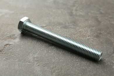 Photo of One metal bolt on grey table, closeup