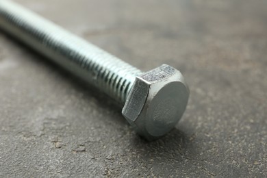 Photo of One metal bolt on grey table, closeup