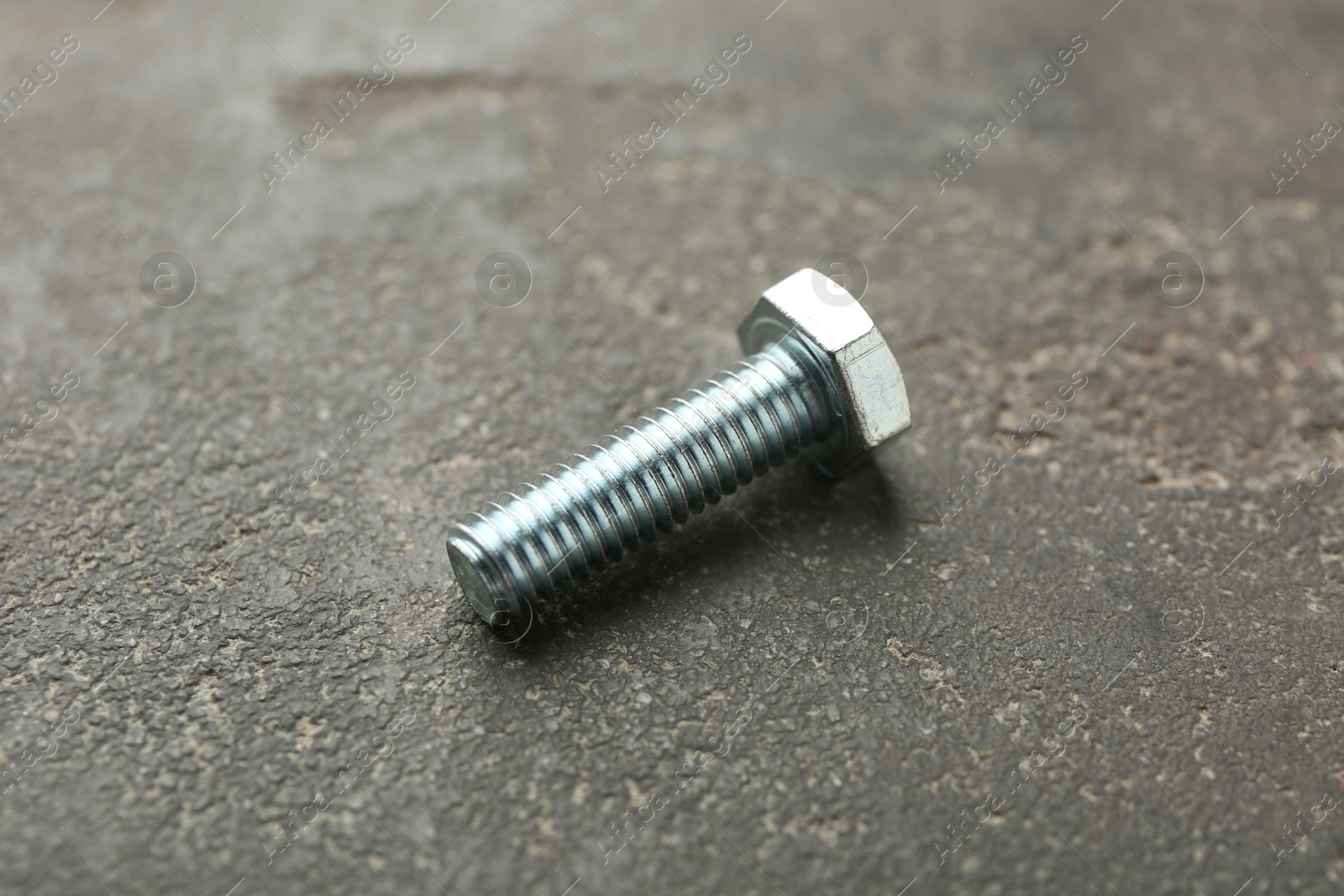 One metal bolt on grey table, closeup Photo of One metal bolt on grey table, closeup