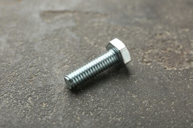 Photo of One metal bolt on grey table, closeup