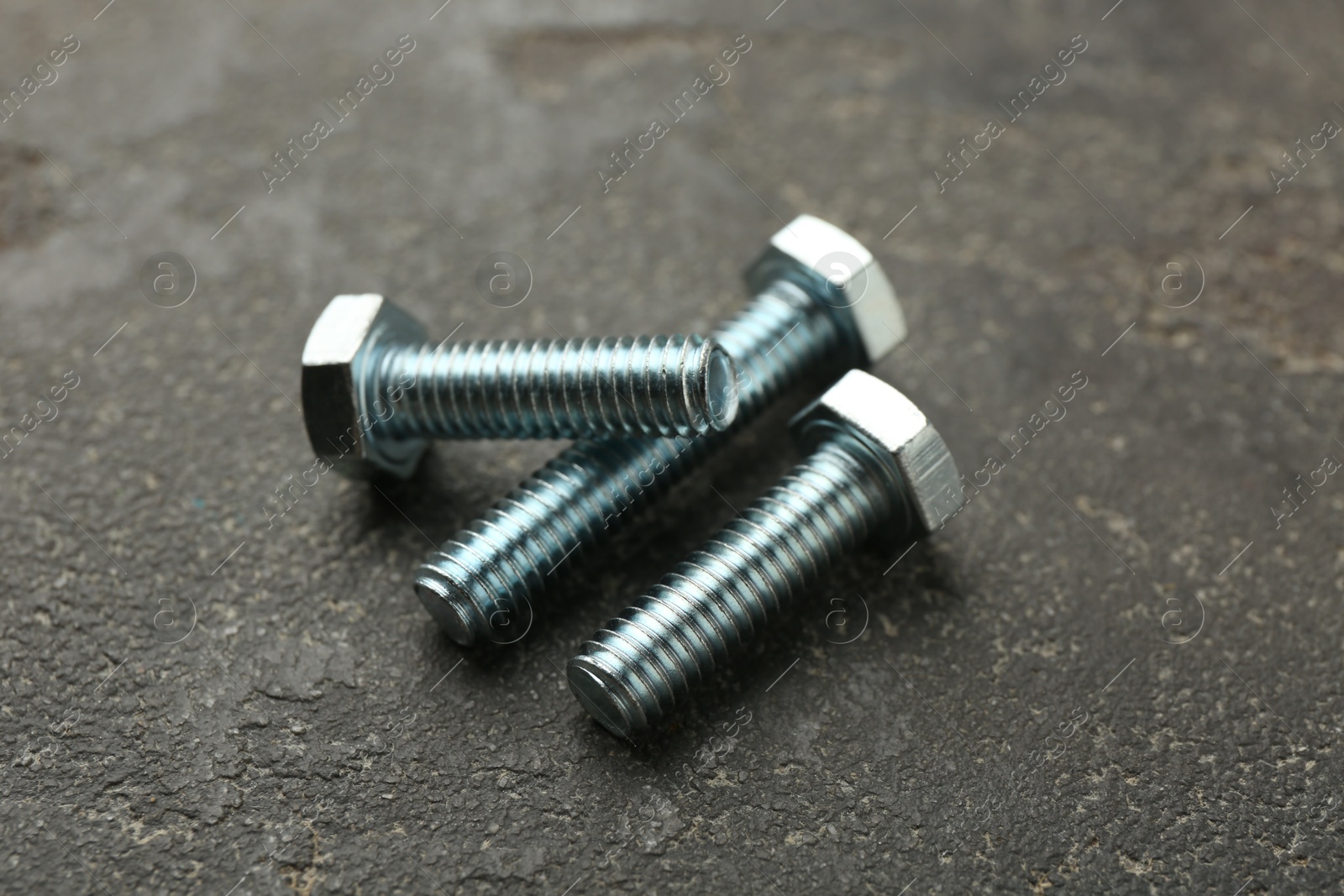 Three metal bolts on grey table, closeup Photo of Three metal bolts on grey table, closeup