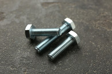 Photo of Three metal bolts on grey table, closeup