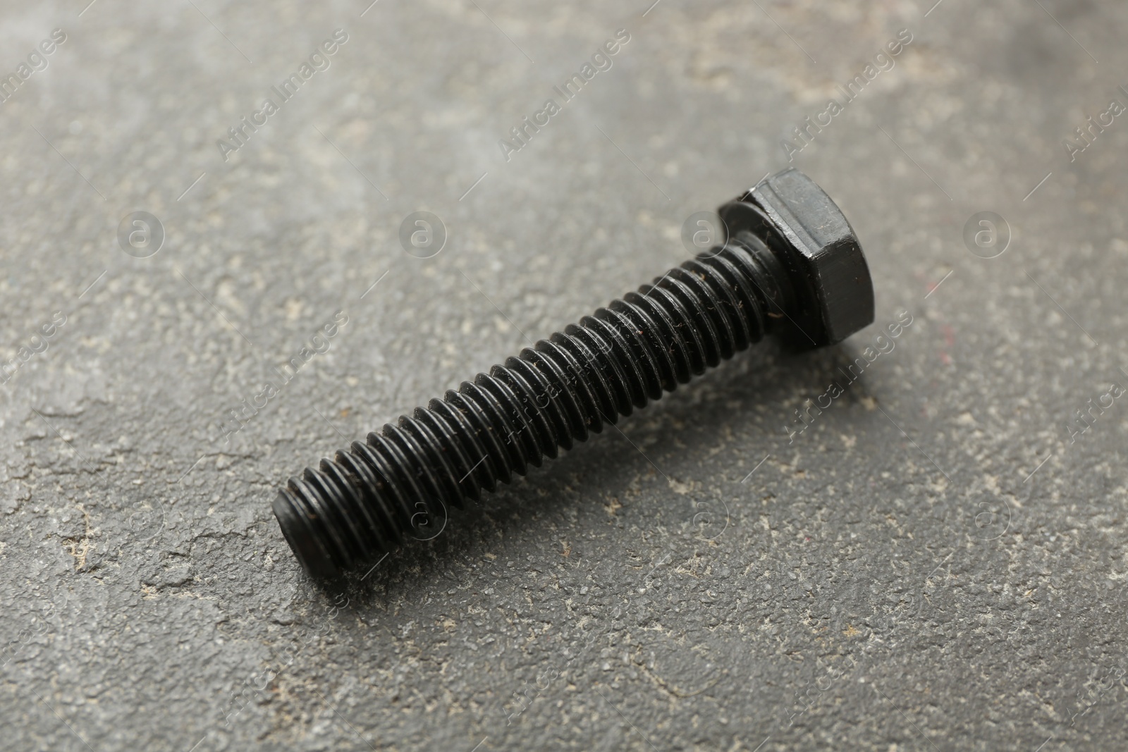 One metal bolt on grey table, closeup Photo of One metal bolt on grey table, closeup