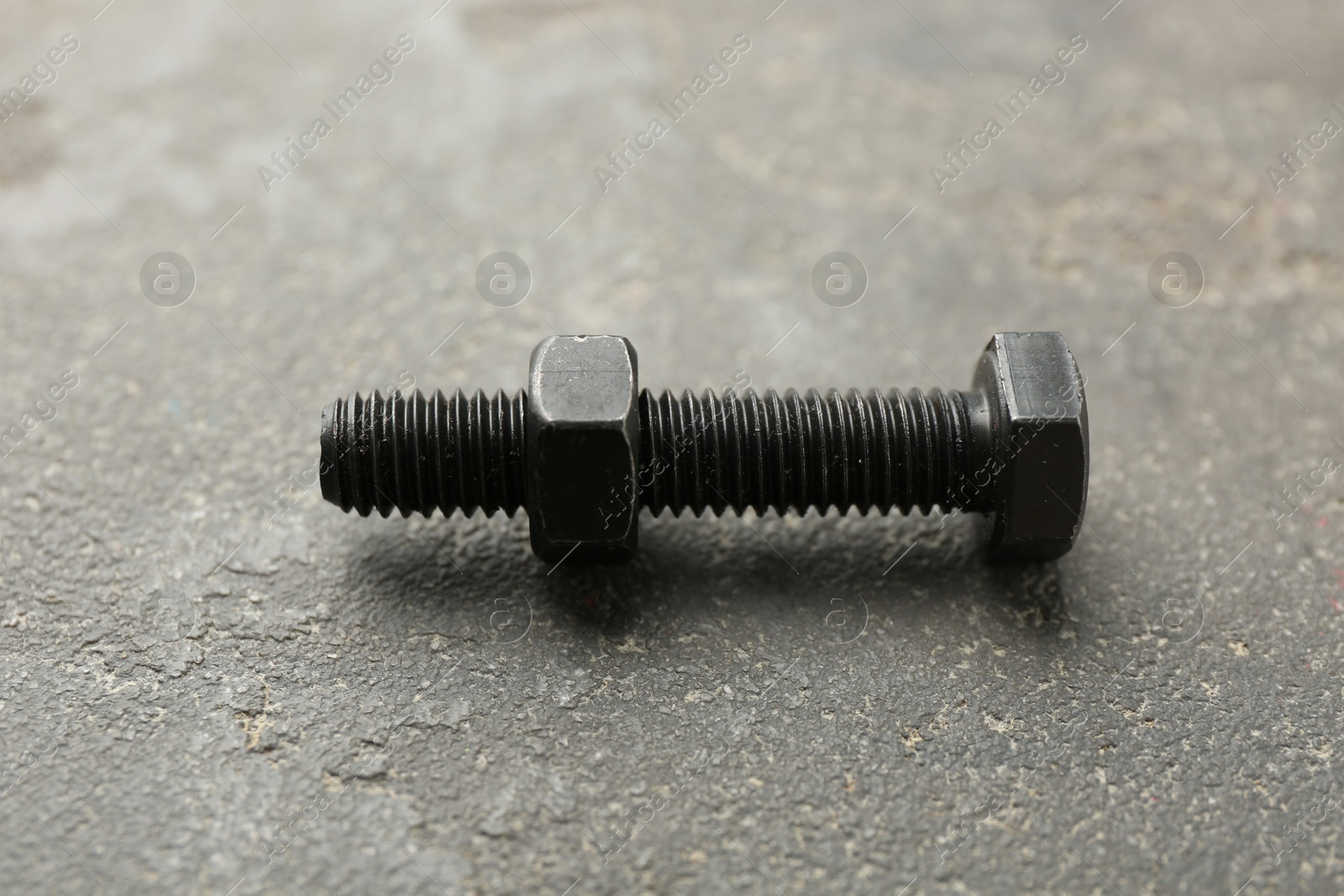 Metal bolt and nut on grey table, closeup Photo of Metal bolt and nut on grey table, closeup