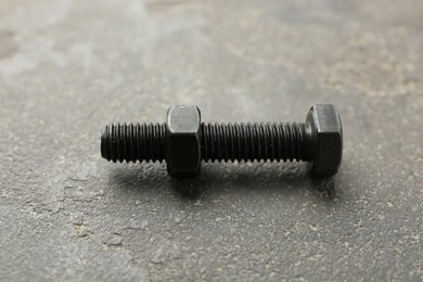Photo of Metal bolt and nut on grey table, closeup
