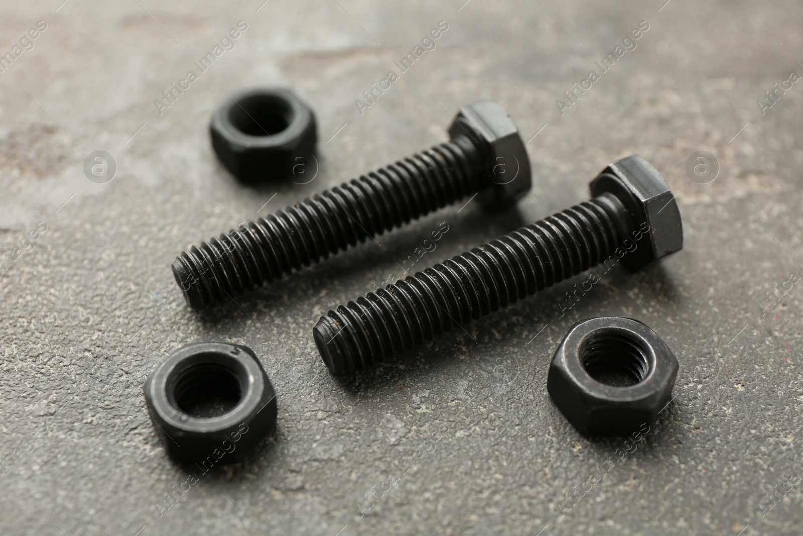 Metal bolts and nuts on grey table, closeup Photo of Metal bolts and nuts on grey table, closeup