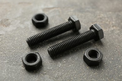 Photo of Metal bolts and nuts on grey table, closeup