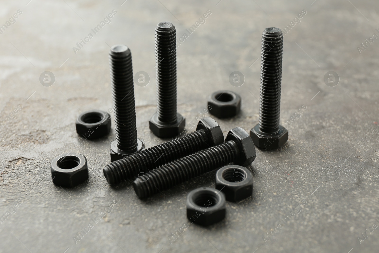 Metal bolts and nuts on grey table, closeup Photo of Metal bolts and nuts on grey table, closeup