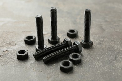 Photo of Metal bolts and nuts on grey table, closeup