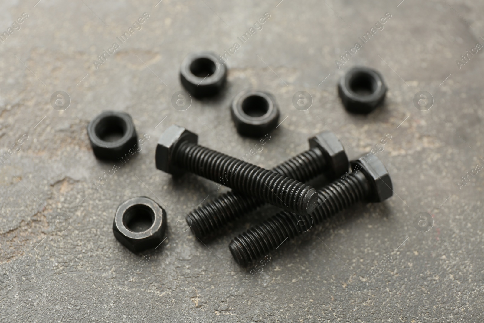 Metal bolts and nuts on grey table, closeup Photo of Metal bolts and nuts on grey table, closeup