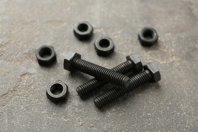 Photo of Metal bolts and nuts on grey table, closeup