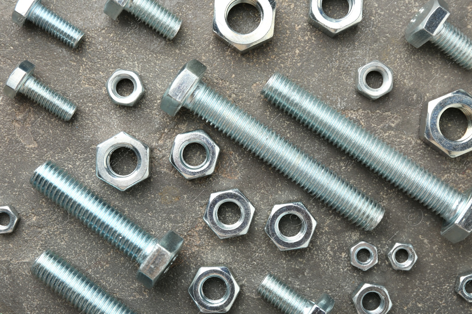 Metal bolts and nuts on grey table, flat lay Photo of Metal bolts and nuts on grey table, flat lay