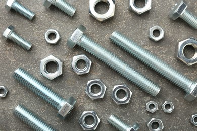 Photo of Metal bolts and nuts on grey table, flat lay