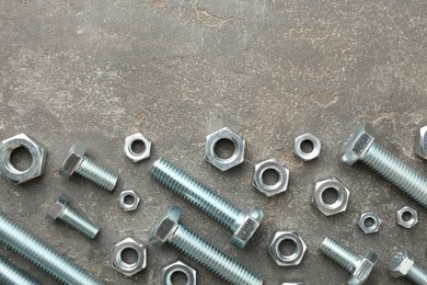 Photo of Metal bolts and nuts on grey table, flat lay. Space for text