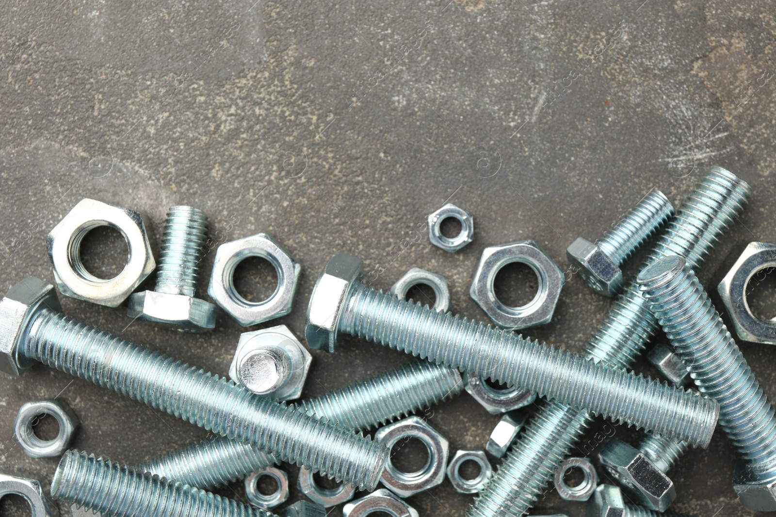 Metal bolts and nuts on grey table, flat lay. Space for text Photo of Metal bolts and nuts on grey table, flat lay. Space for text
