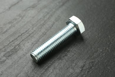 Photo of One metal bolt on black table, closeup