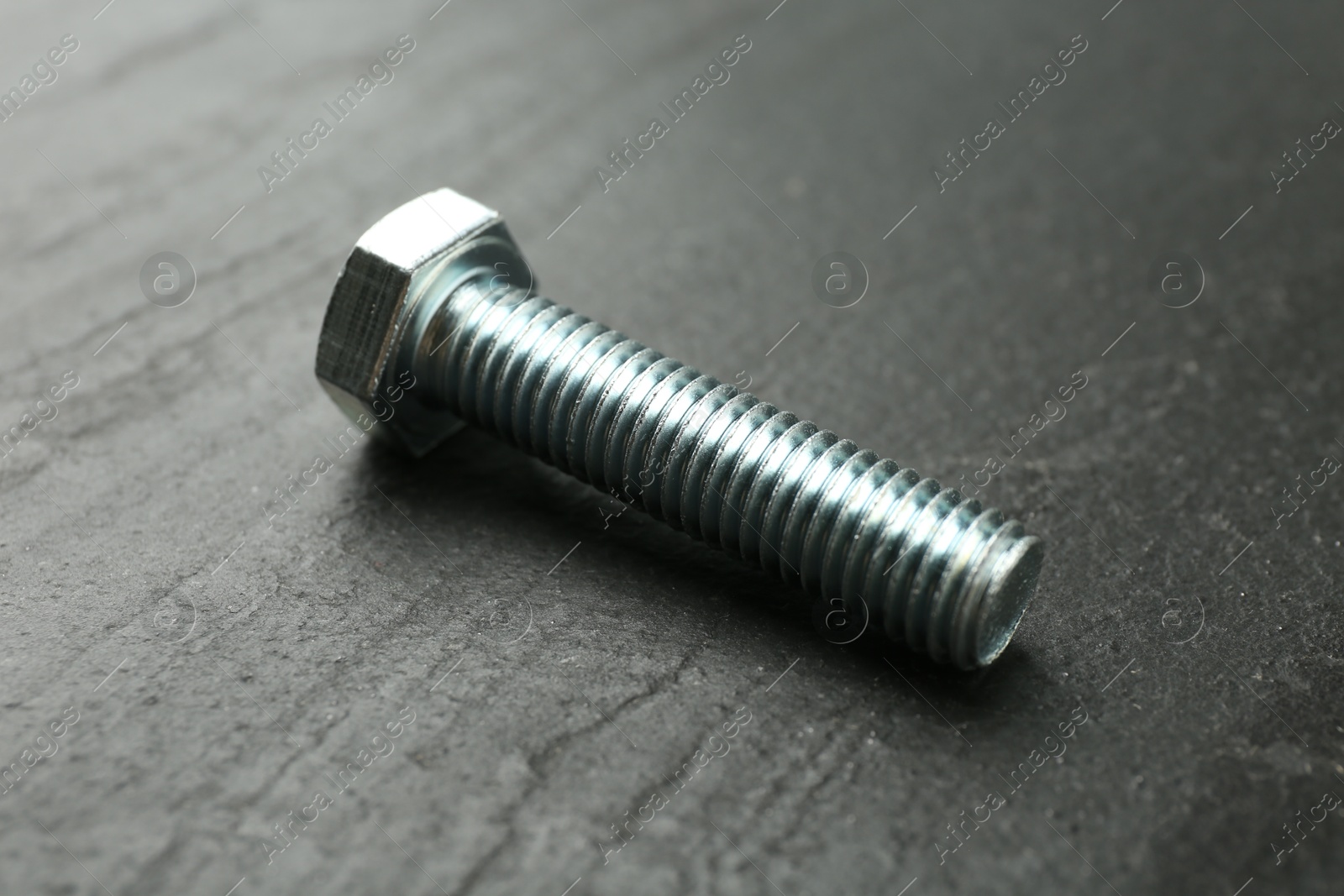 One metal bolt on black table, closeup Photo of One metal bolt on black table, closeup