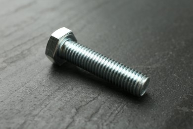 Photo of One metal bolt on black table, closeup