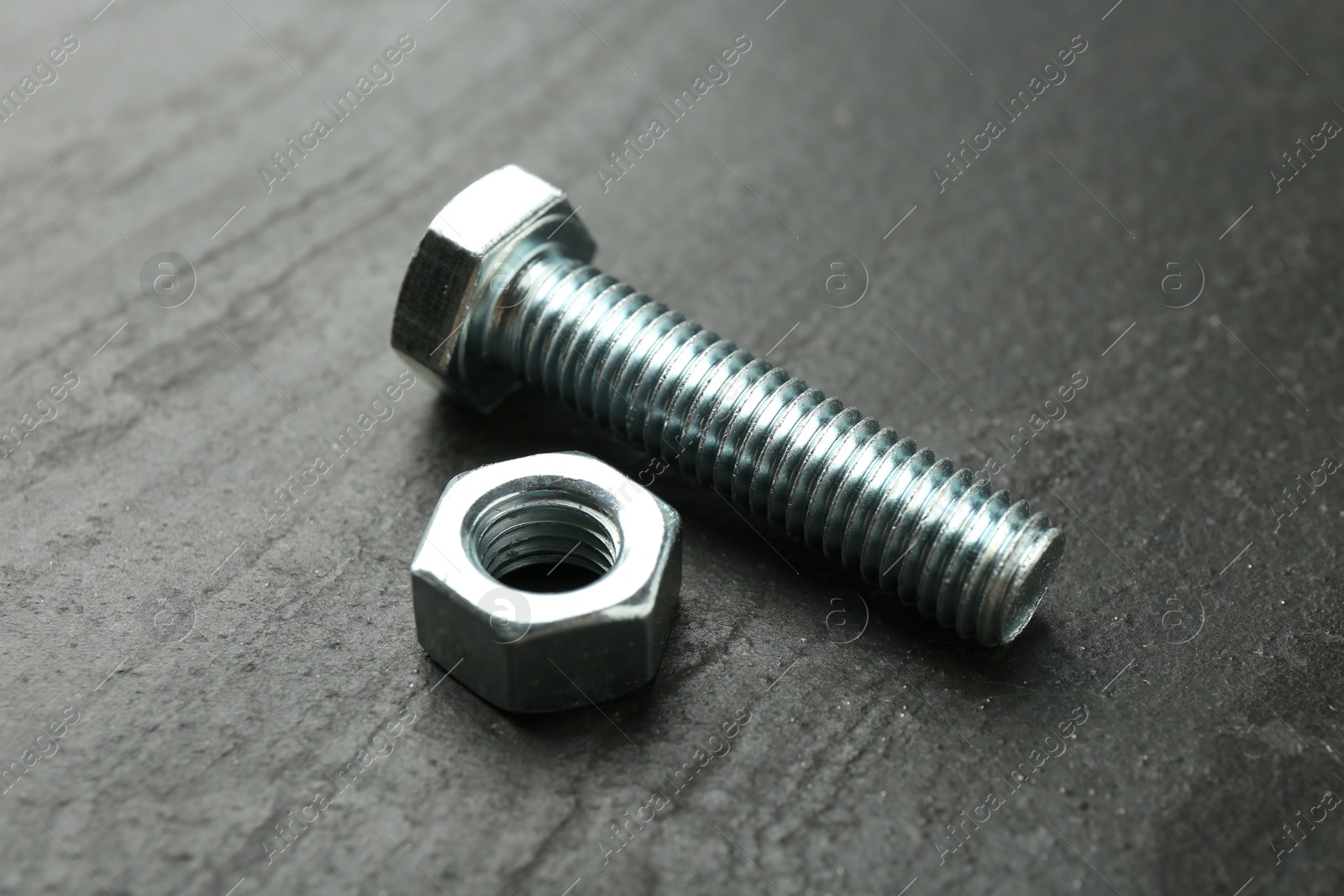 Metal bolt and nut on black table, closeup Photo of Metal bolt and nut on black table, closeup