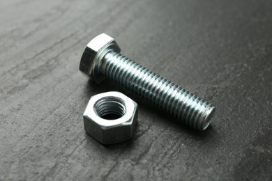 Photo of Metal bolt and nut on black table, closeup
