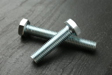 Photo of Two metal bolts on black table, closeup
