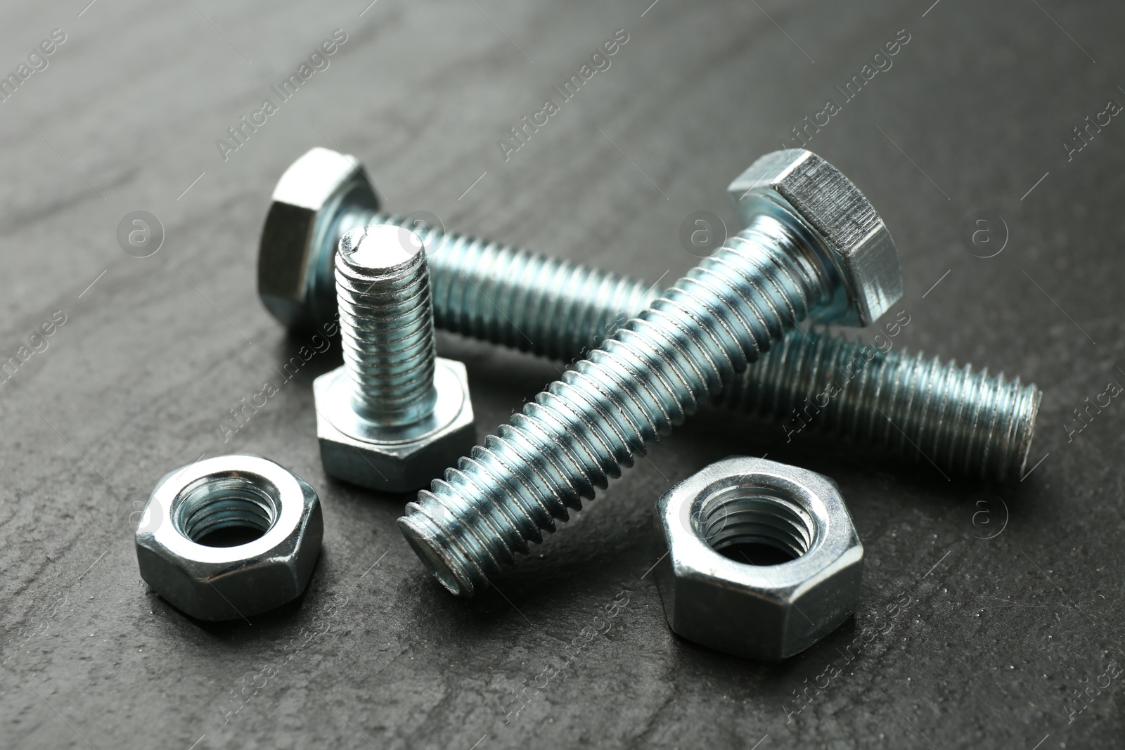 Metal bolts and nuts on black table, closeup Photo of Metal bolts and nuts on black table, closeup