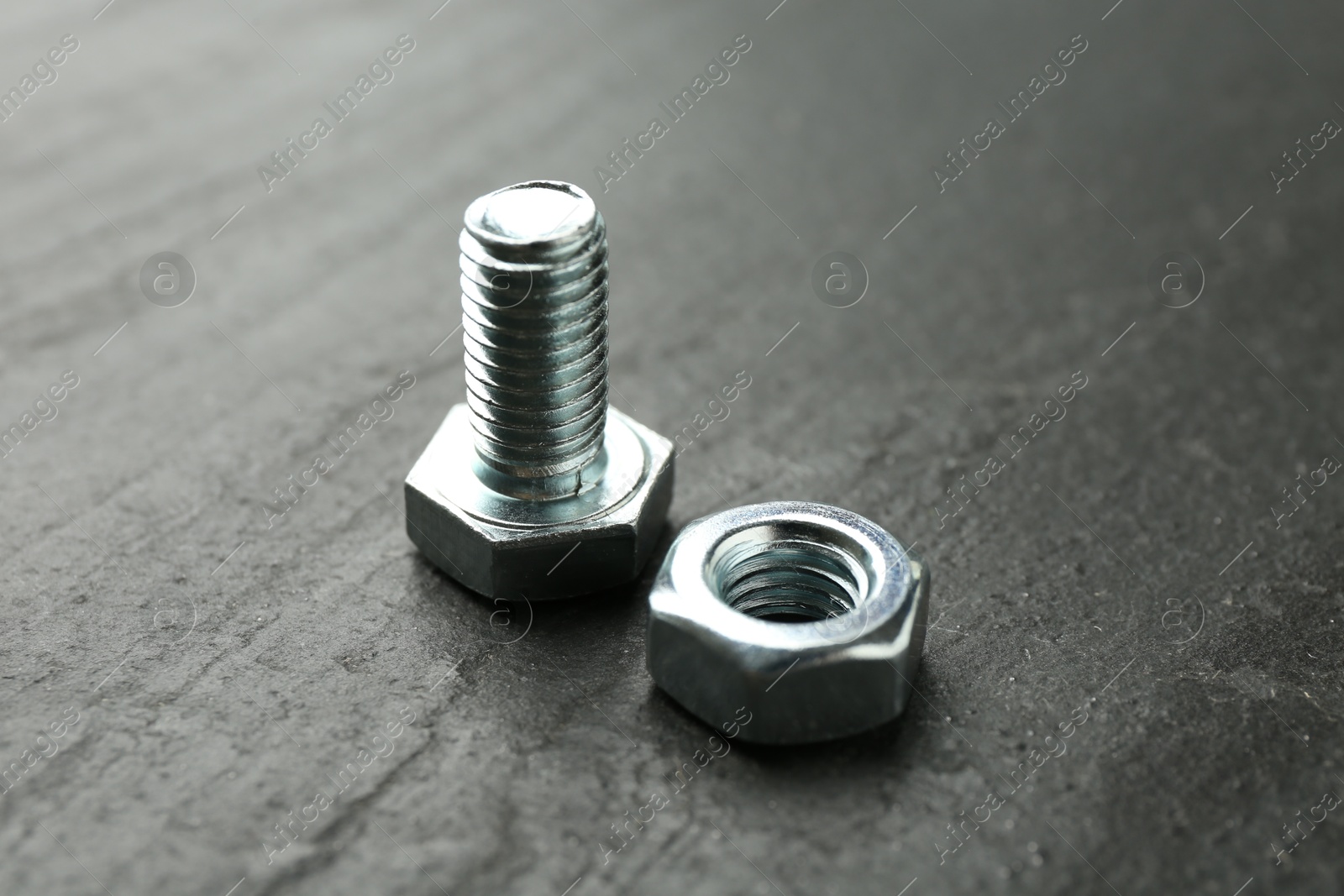Metal bolt and nut on black table, closeup Photo of Metal bolt and nut on black table, closeup