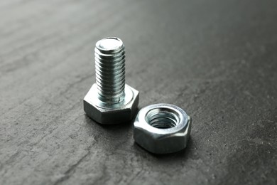 Photo of Metal bolt and nut on black table, closeup