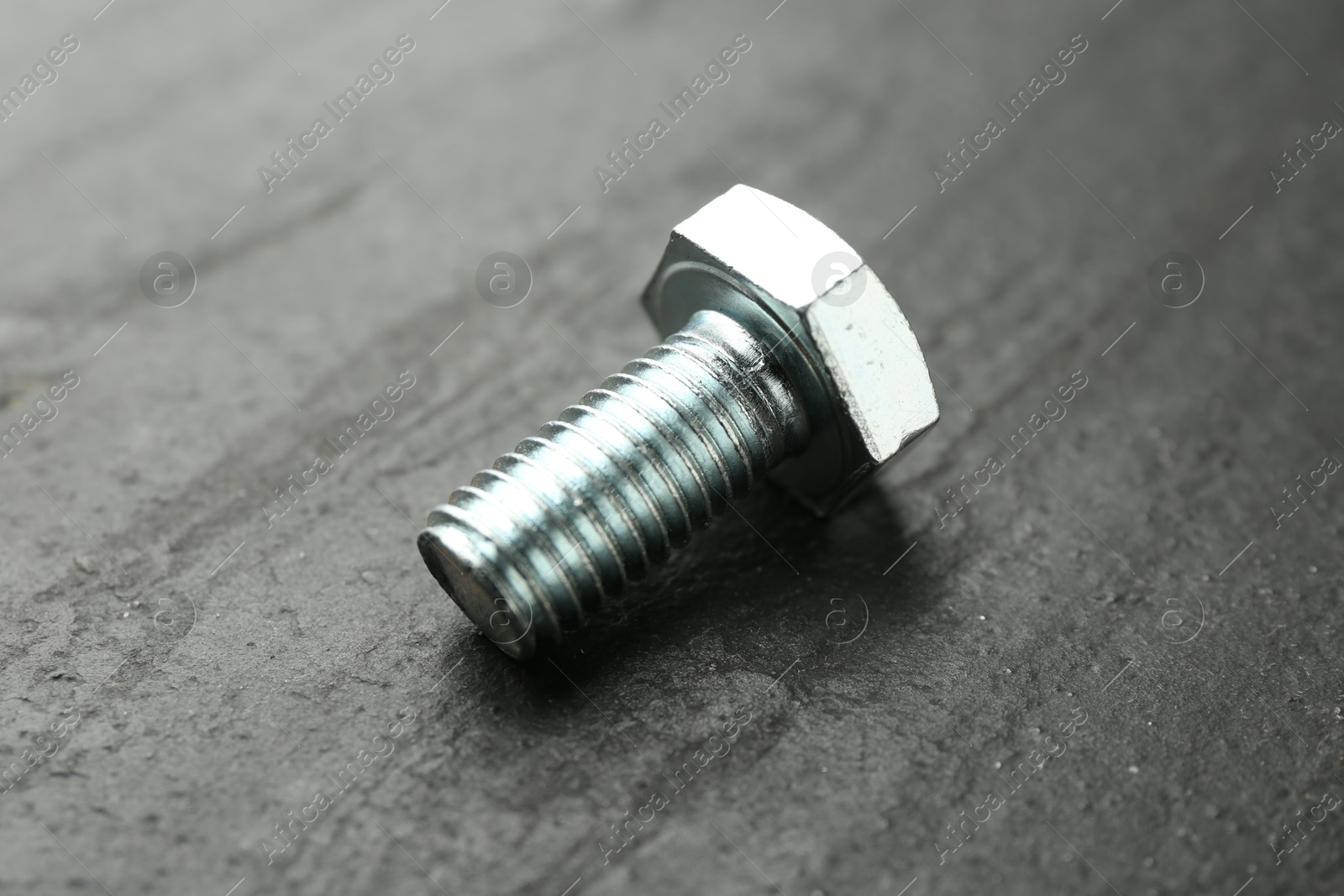 One metal bolt on black table, closeup Photo of One metal bolt on black table, closeup