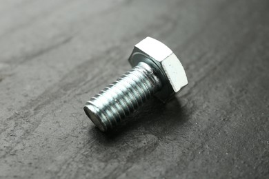 Photo of One metal bolt on black table, closeup