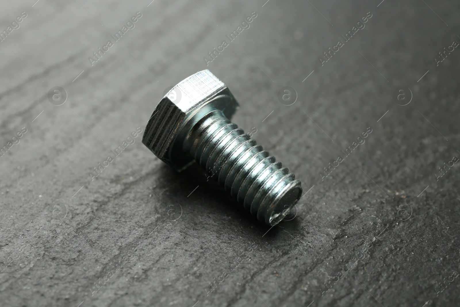 One metal bolt on black table, closeup Photo of One metal bolt on black table, closeup