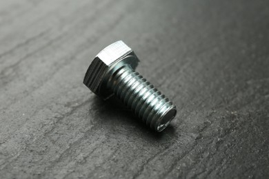 Photo of One metal bolt on black table, closeup