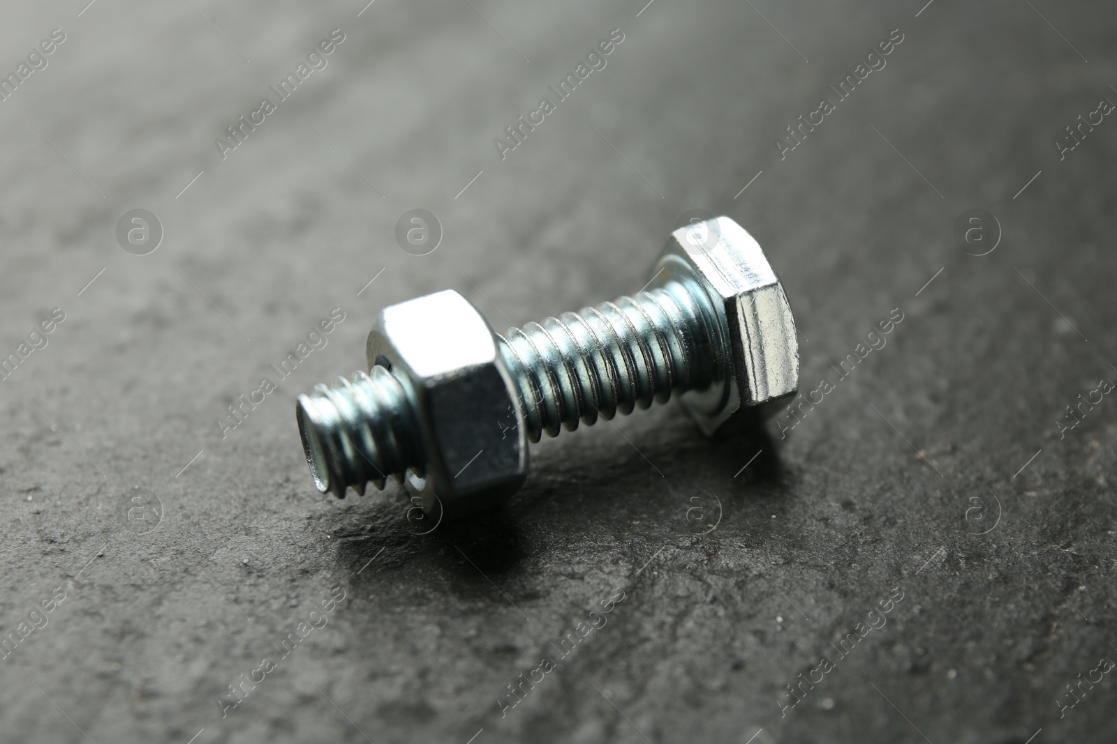 Metal bolt and nut on black table, closeup Photo of Metal bolt and nut on black table, closeup