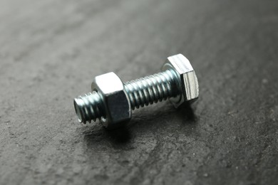 Photo of Metal bolt and nut on black table, closeup