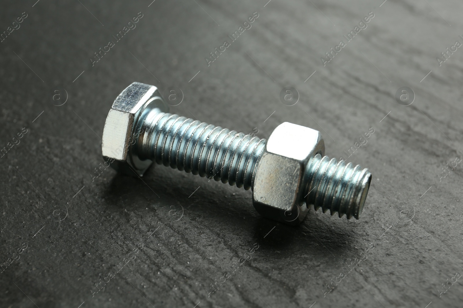 Metal bolt and nut on black table, closeup Photo of Metal bolt and nut on black table, closeup