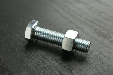 Photo of Metal bolt and nut on black table, closeup