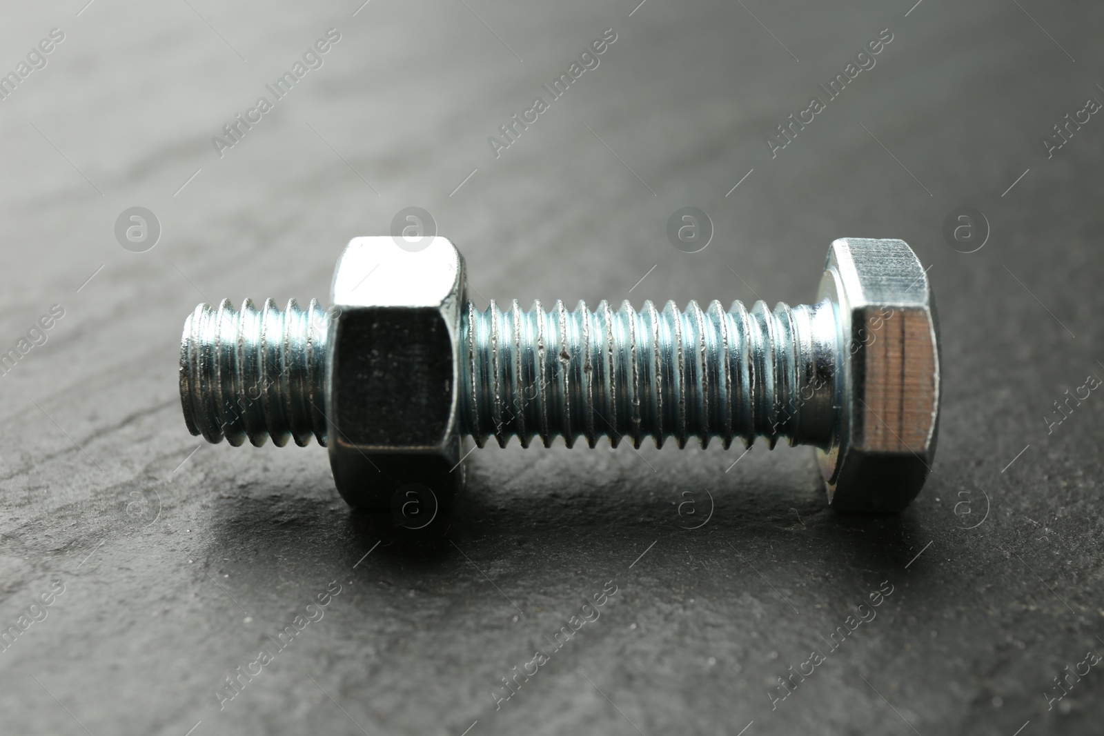 Metal bolt and nut on black table, closeup Photo of Metal bolt and nut on black table, closeup