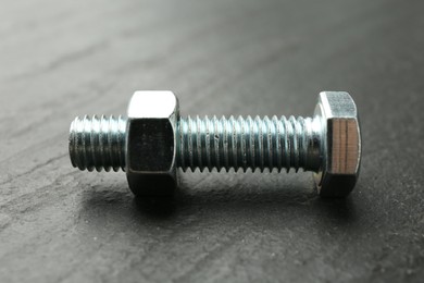 Photo of Metal bolt and nut on black table, closeup