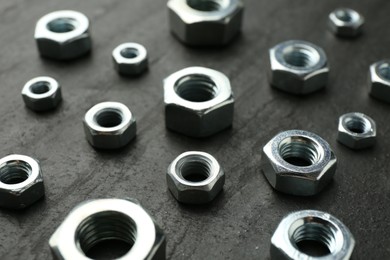 Photo of Metal hex nuts on black table, closeup