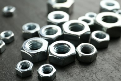 Photo of Metal hex nuts on black table, closeup