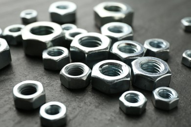 Photo of Metal hex nuts on black table, closeup