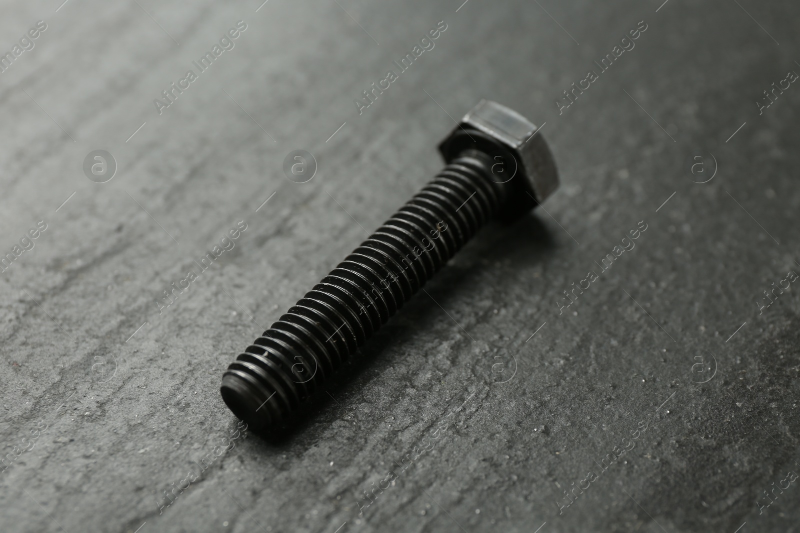 One metal bolt on black table, closeup Photo of One metal bolt on black table, closeup