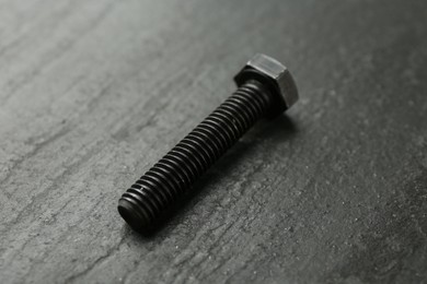 Photo of One metal bolt on black table, closeup