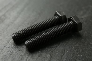 Photo of Two metal bolts on black table, closeup