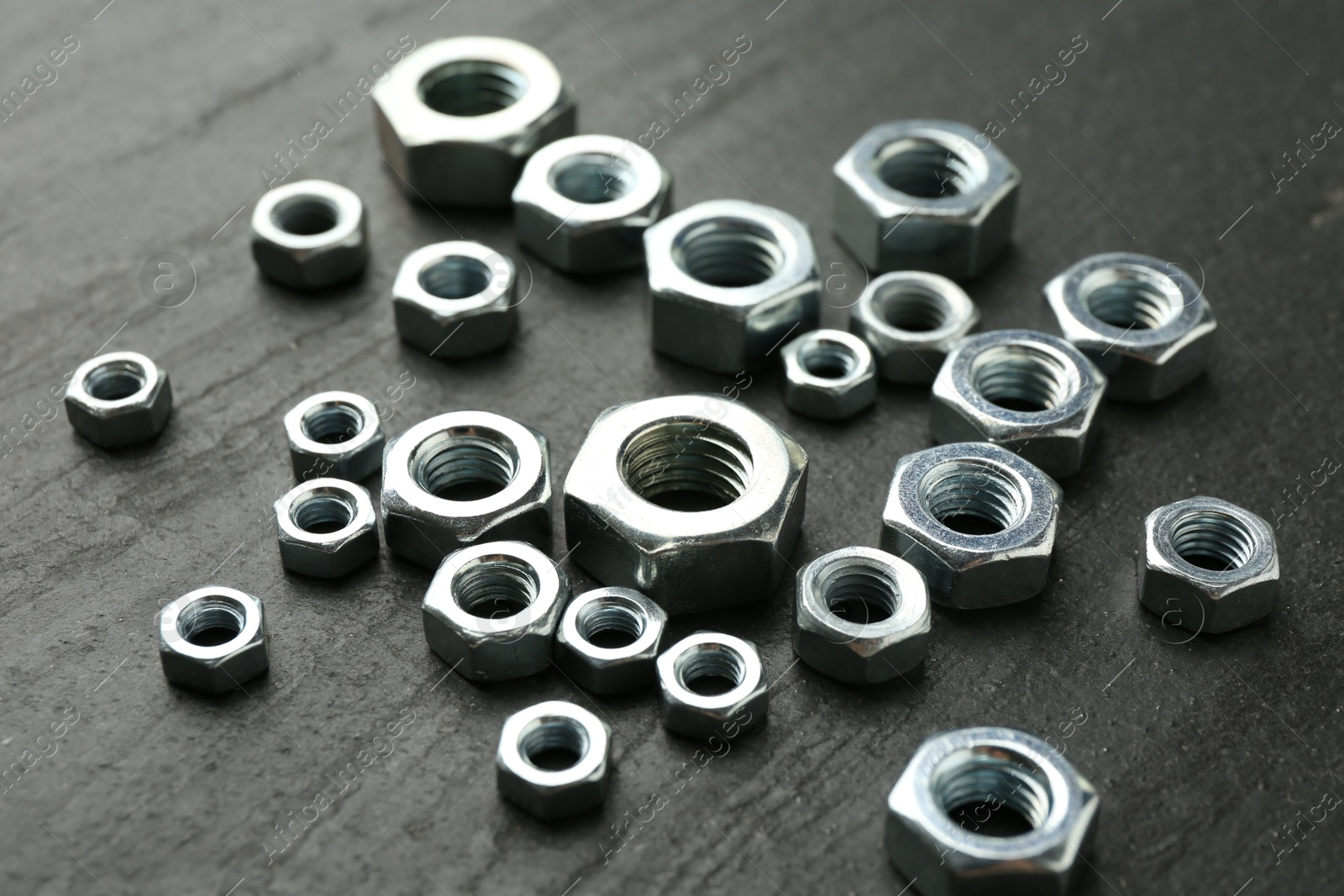 Metal hex nuts on black table, closeup Photo of Metal hex nuts on black table, closeup