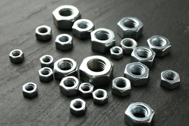 Photo of Metal hex nuts on black table, closeup