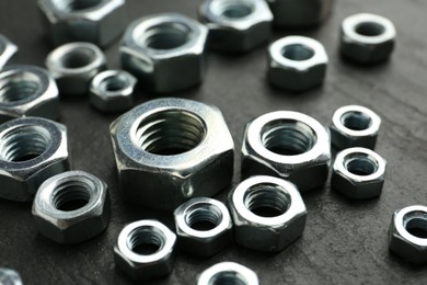 Photo of Metal hex nuts on black table, closeup