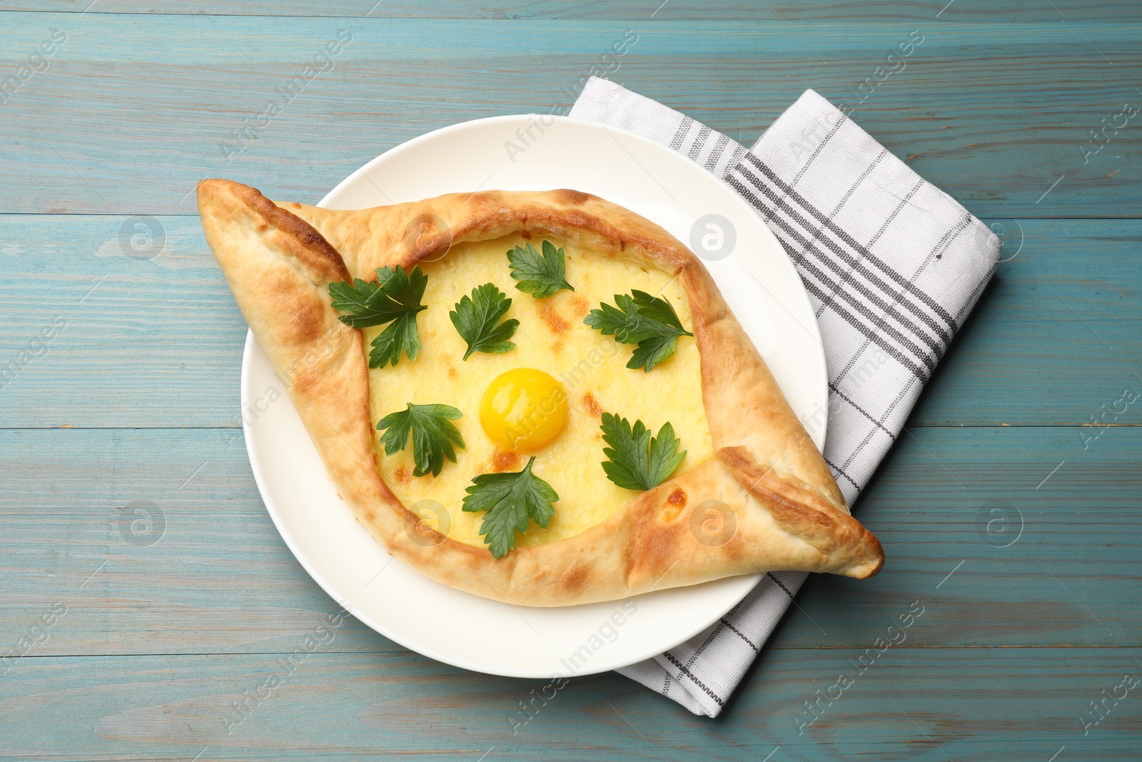 Tasty khachapuri with cheese, egg and parsley on light blue wooden table, top view Photo of Tasty khachapuri with cheese, egg and parsley on light blue wooden table, top view