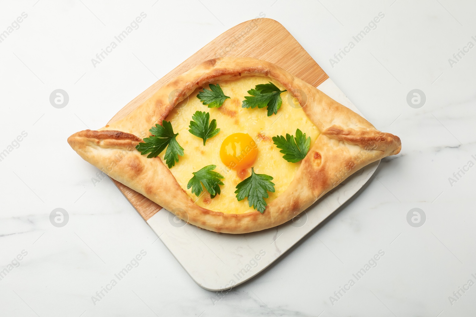 Tasty khachapuri with cheese, egg and parsley on white marble table, top view Photo of Tasty khachapuri with cheese, egg and parsley on white marble table, top view