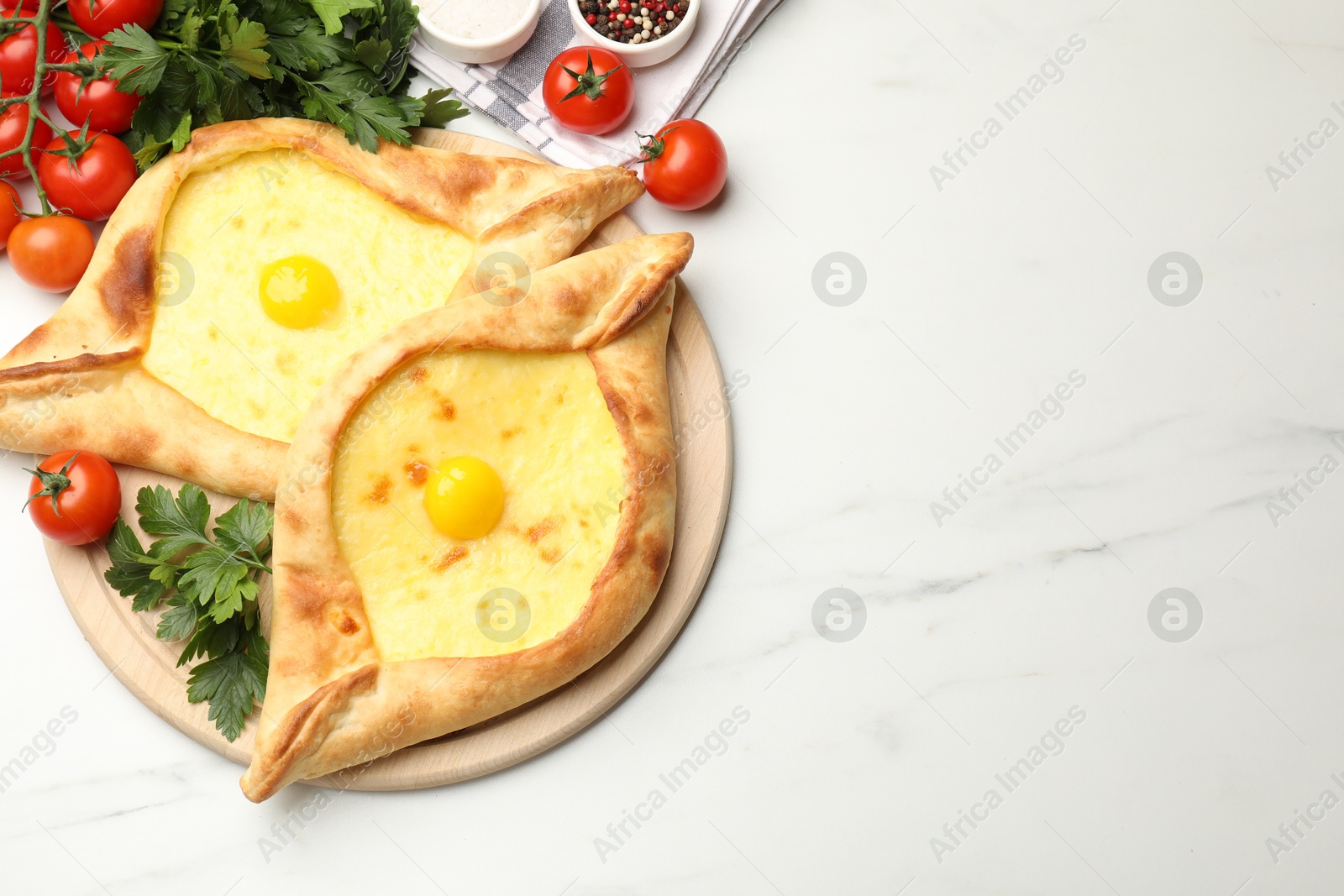 Tasty khachapuris with cheese, eggs, tomatoes, parsley and spices on white marble table, flat lay. space for text Photo of Tasty khachapuris with cheese, eggs, tomatoes, parsley and spices on white marble table, flat lay. space for text